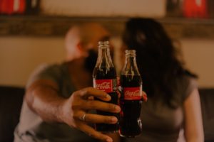 a couple holding two bottles of coke